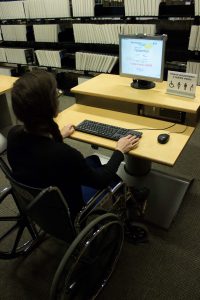Usager en fauteuil utilisant un poste de recherche