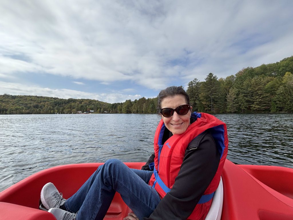 Personne portant un gilet de sauvetage rouge profitant d’une balade en pédalo sur le lac Morgan, entouré de forêt. Activité nautique accessible aux Chalets Lanaudière.