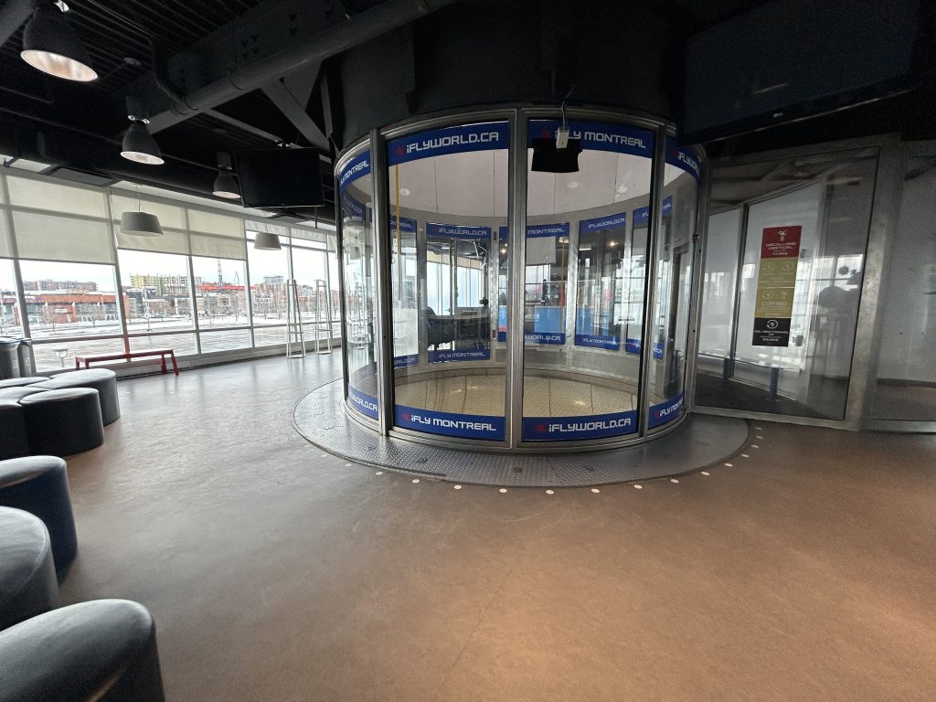 Simulateur de chute libre en intérieur chez iFLY Montréal, espace moderne avec parois vitrées, conçu pour des activités inclusives.